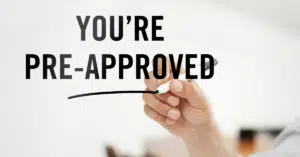 A hand holding a pen underlining the words 'You're Pre-Approved,' representing a successful mortgage pre-approval step in the home-buying process.