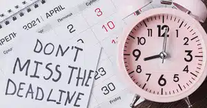 Close-up of a calendar with the 10th highlighted and a pink alarm clock beside a note that says 'DON’T MISS THE MORTGAGE DEADLINE.'