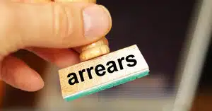 Close-up of a hand holding a rubber stamp with the word 'mortgage arrears' printed on it.